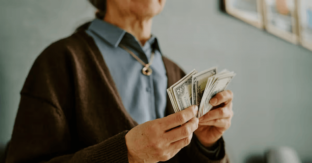 Senior woman holding counting money dollar bills 1200x628 facebook